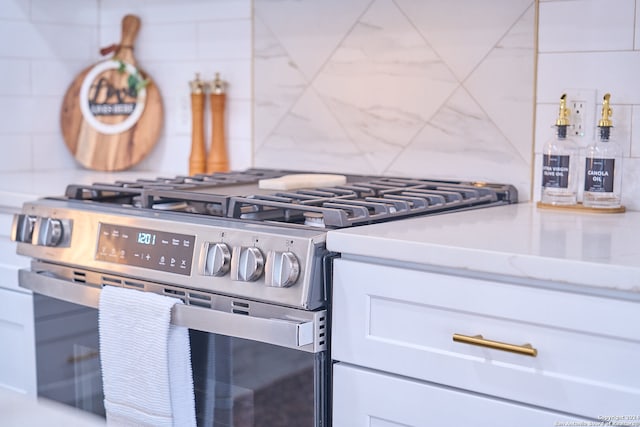 interior details featuring gas stove, white cabinetry, and backsplash