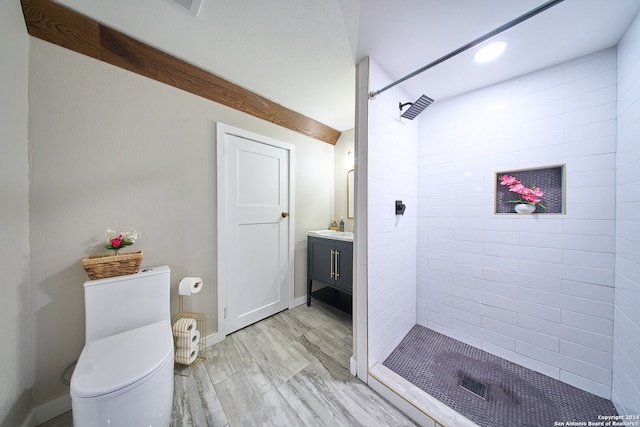 bathroom featuring hardwood / wood-style floors, vanity, toilet, and tiled shower