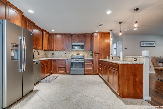 kitchen with kitchen peninsula, light stone counters, stainless steel appliances, sink, and hanging light fixtures