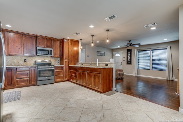 kitchen with kitchen peninsula, stainless steel appliances, ceiling fan, decorative light fixtures, and light hardwood / wood-style flooring