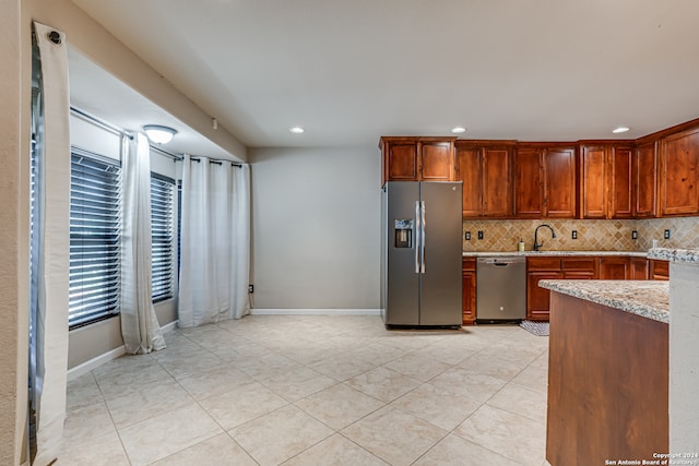 kitchen featuring light stone countertops, sink, stainless steel appliances, tasteful backsplash, and light tile patterned flooring