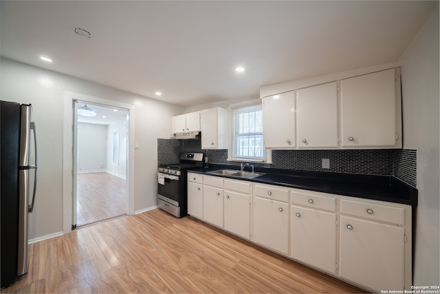 kitchen with appliances with stainless steel finishes, backsplash, sink, light hardwood / wood-style flooring, and white cabinets