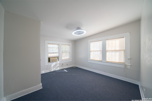 spare room featuring dark colored carpet, vaulted ceiling, and cooling unit