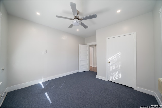 unfurnished bedroom with dark carpet and ceiling fan