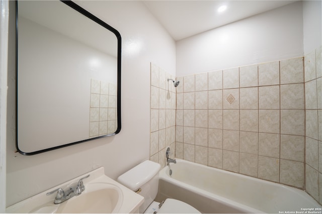 full bathroom with tiled shower / bath combo, toilet, and sink