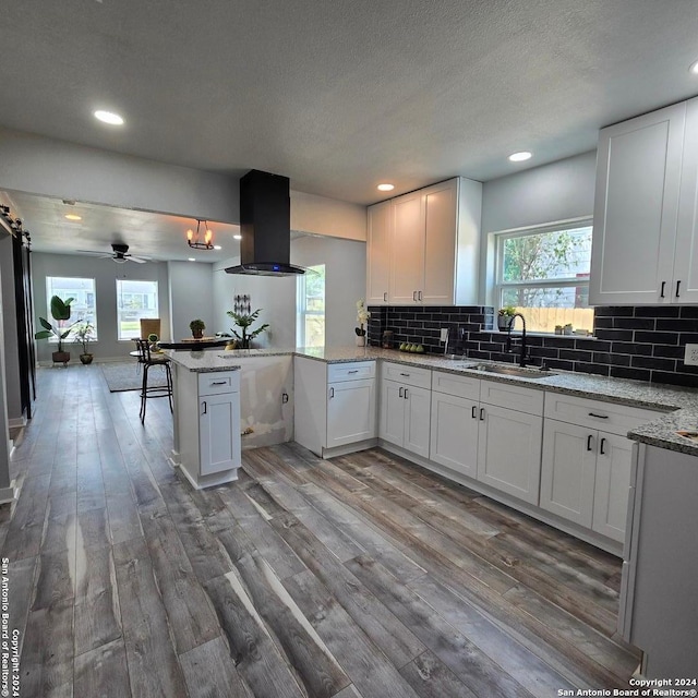 kitchen featuring kitchen peninsula, white cabinetry, sink, and extractor fan