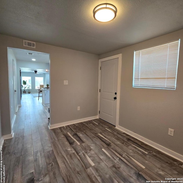 empty room with a textured ceiling and dark hardwood / wood-style floors