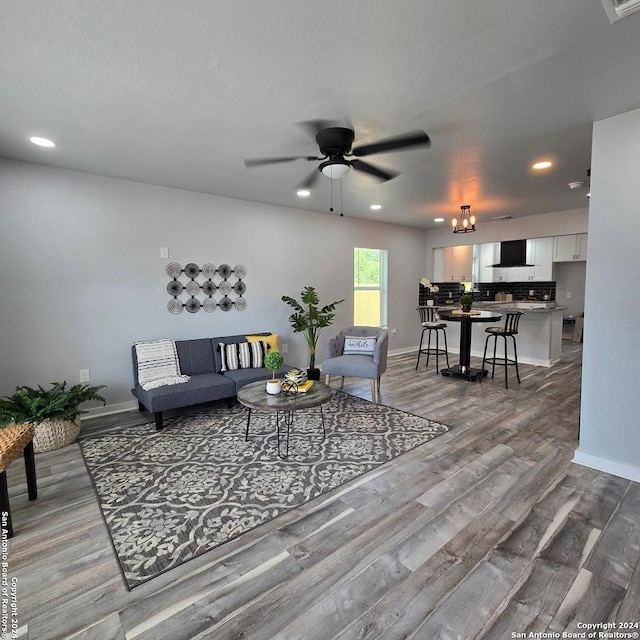 living room featuring hardwood / wood-style flooring and ceiling fan with notable chandelier