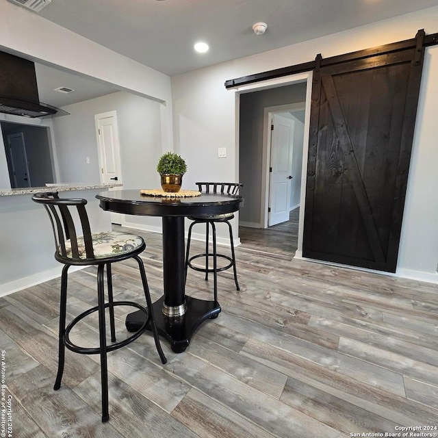 dining room with a barn door and hardwood / wood-style flooring