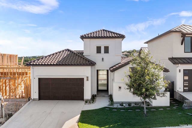 mediterranean / spanish-style house featuring a garage and a front lawn