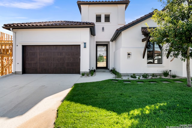 mediterranean / spanish house featuring a garage and a front yard