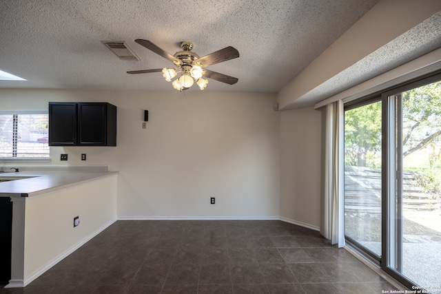 kitchen with a textured ceiling, dark tile patterned flooring, and ceiling fan