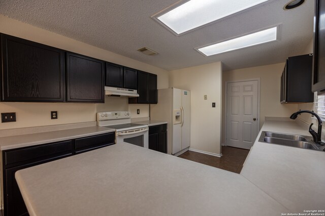 kitchen with a textured ceiling, sink, and white appliances