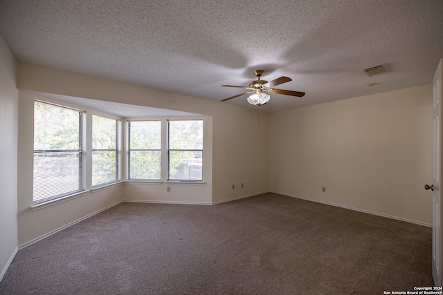 spare room featuring dark colored carpet, a textured ceiling, and ceiling fan