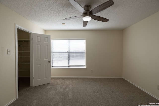 unfurnished bedroom with a closet, a walk in closet, carpet floors, and ceiling fan