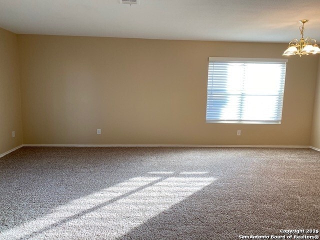 empty room featuring carpet flooring and a chandelier