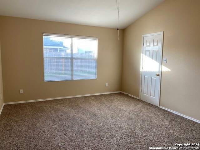 carpeted spare room featuring vaulted ceiling