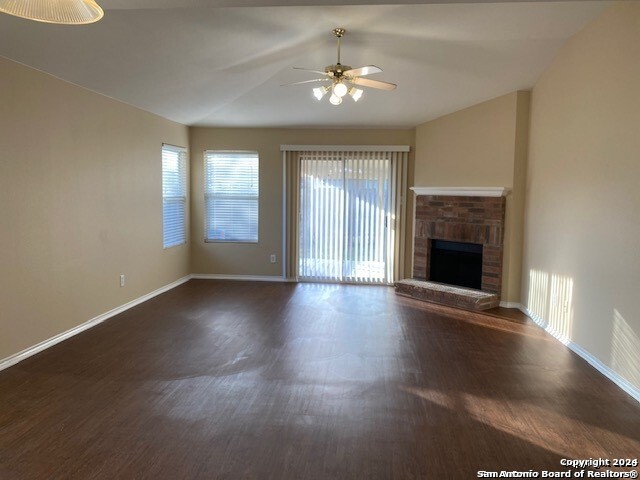 unfurnished living room with ceiling fan, a fireplace, and dark hardwood / wood-style floors