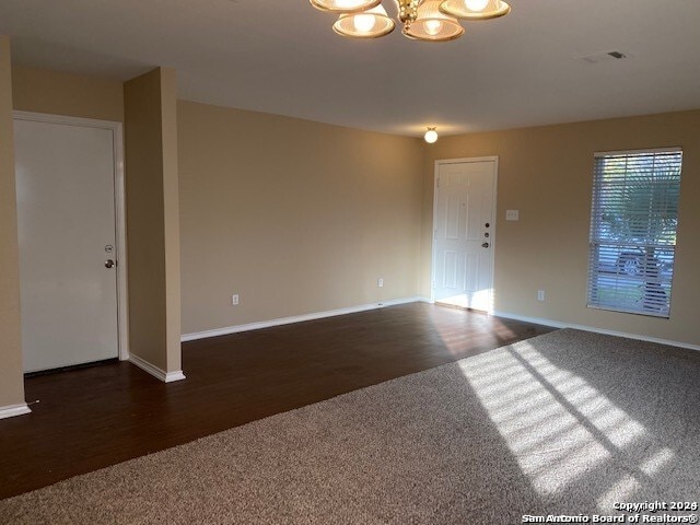 spare room with dark wood-type flooring and a chandelier