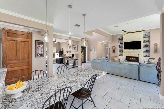 dining space with crown molding, ceiling fan, built in features, a fireplace, and light tile patterned floors