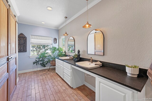 bathroom with hardwood / wood-style flooring, vanity, ornamental molding, and a textured ceiling