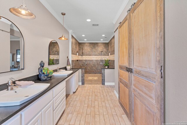 bathroom with hardwood / wood-style flooring, tiled shower, crown molding, and vanity