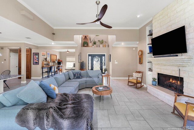 living room featuring ceiling fan, a fireplace, light tile patterned floors, and ornamental molding