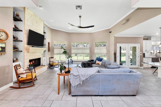 tiled living room with built in shelves, ornamental molding, ceiling fan, and a healthy amount of sunlight