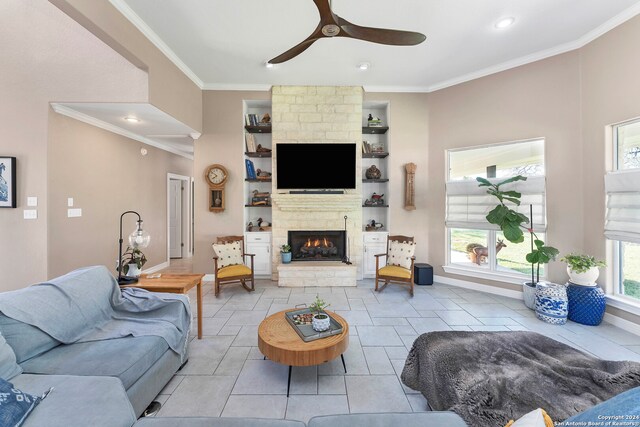 tiled living room with a large fireplace, ceiling fan, a healthy amount of sunlight, and ornamental molding