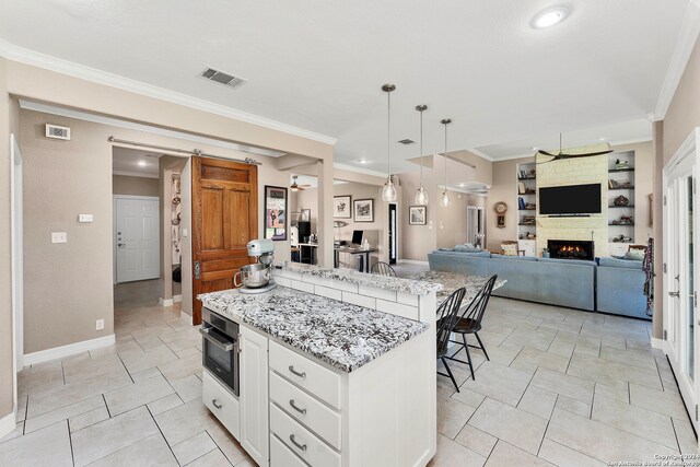 kitchen featuring a kitchen island, crown molding, oven, decorative light fixtures, and white cabinets