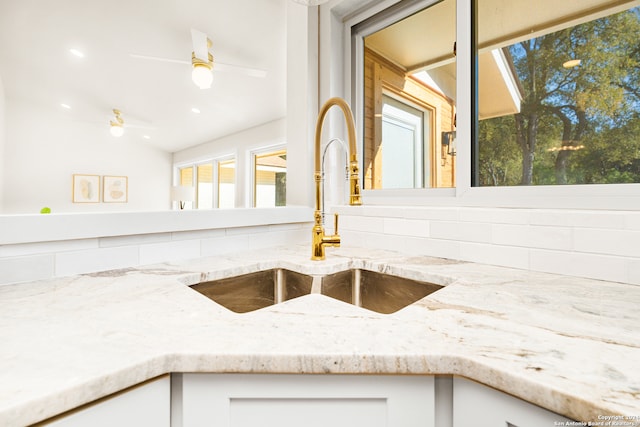 details with light stone counters, sink, white cabinets, and ceiling fan