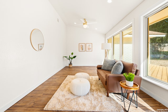 living area with ceiling fan, wood-type flooring, and lofted ceiling