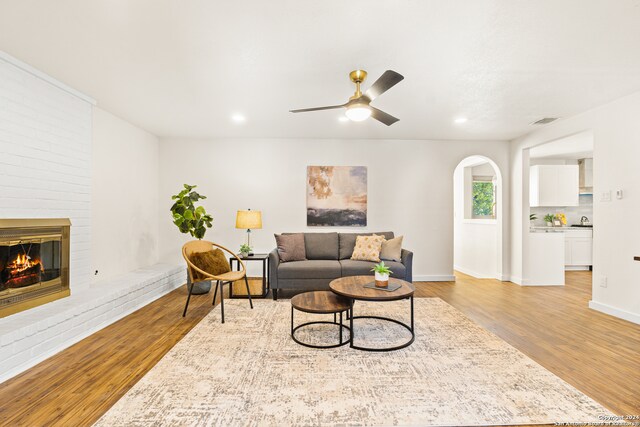 living room with ceiling fan, a fireplace, and light wood-type flooring