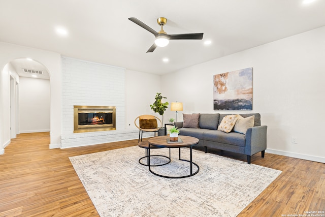 living room featuring a fireplace, light hardwood / wood-style floors, and ceiling fan