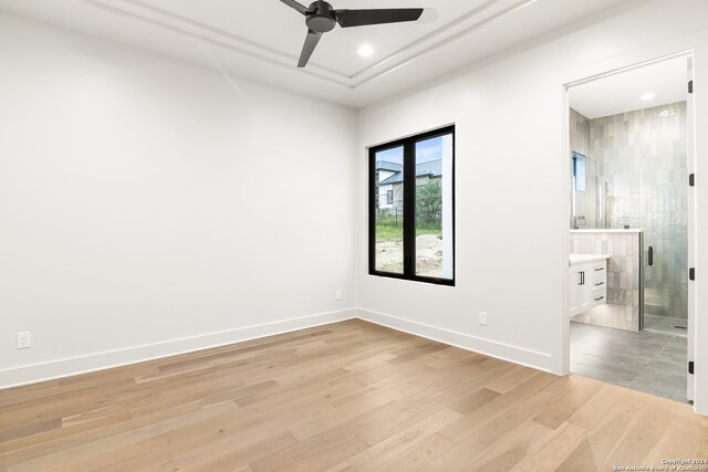 spare room featuring light wood-type flooring, tile walls, and ceiling fan