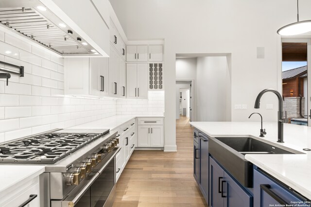 kitchen with blue cabinetry, white cabinetry, hanging light fixtures, premium range hood, and high end stainless steel range