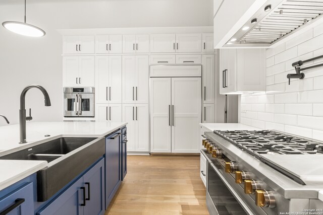 kitchen featuring premium range hood, blue cabinetry, pendant lighting, and premium appliances