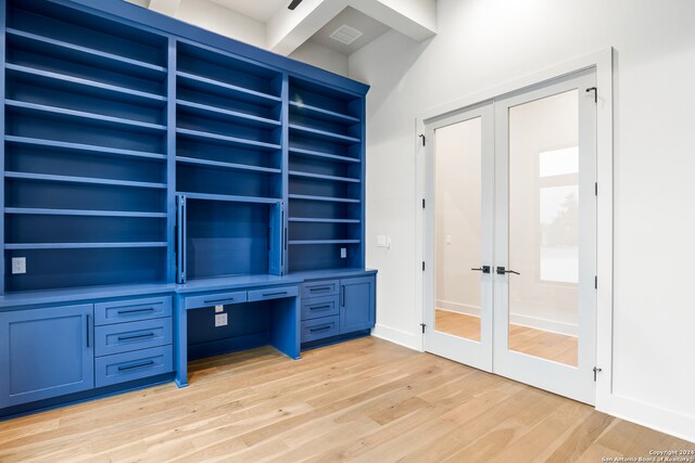 unfurnished office with beamed ceiling, light hardwood / wood-style floors, built in desk, and french doors