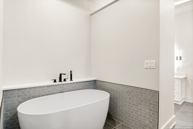 bathroom featuring tile patterned flooring, vanity, a bathing tub, and tile walls