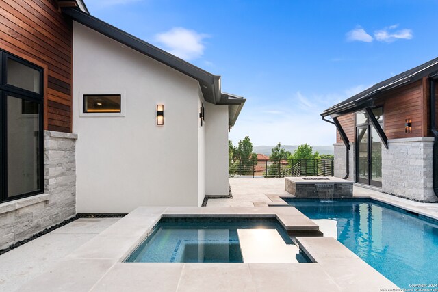 view of swimming pool with an in ground hot tub, pool water feature, and a patio