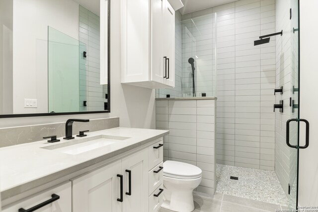 bathroom featuring tile patterned flooring, vanity, toilet, and a shower with shower door