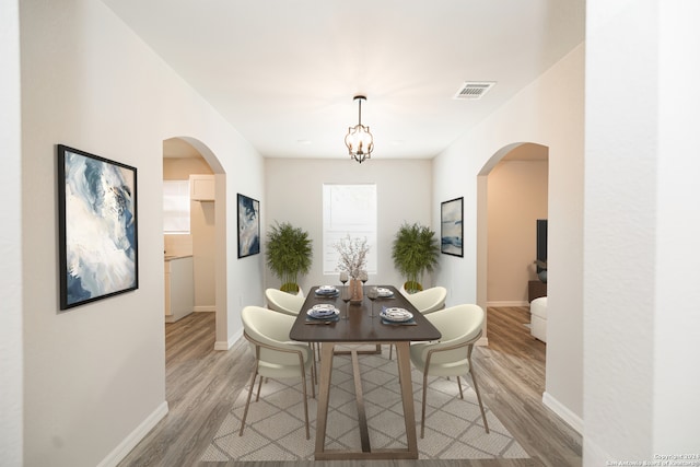 dining room with light hardwood / wood-style flooring and a chandelier