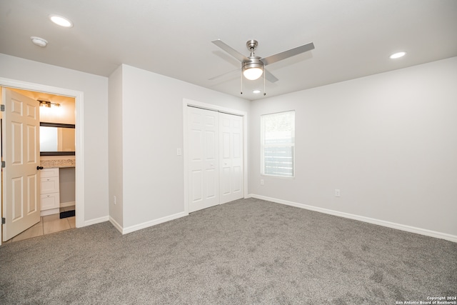 unfurnished bedroom with a closet, ensuite bath, ceiling fan, and light colored carpet