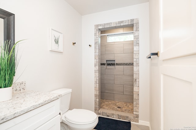 bathroom with vanity, toilet, and tiled shower