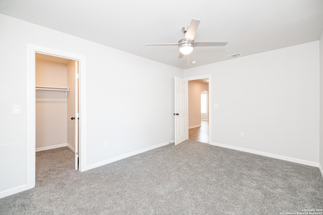 unfurnished bedroom featuring ceiling fan, a spacious closet, carpet floors, and a closet