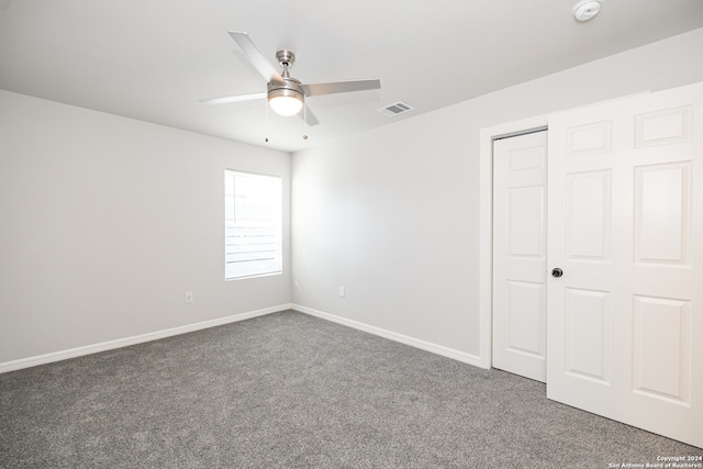 unfurnished bedroom with ceiling fan, dark carpet, and a closet