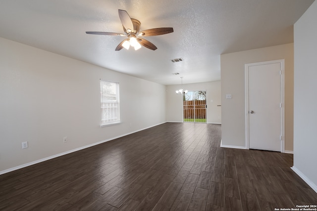 spare room with a textured ceiling, ceiling fan with notable chandelier, and dark hardwood / wood-style floors