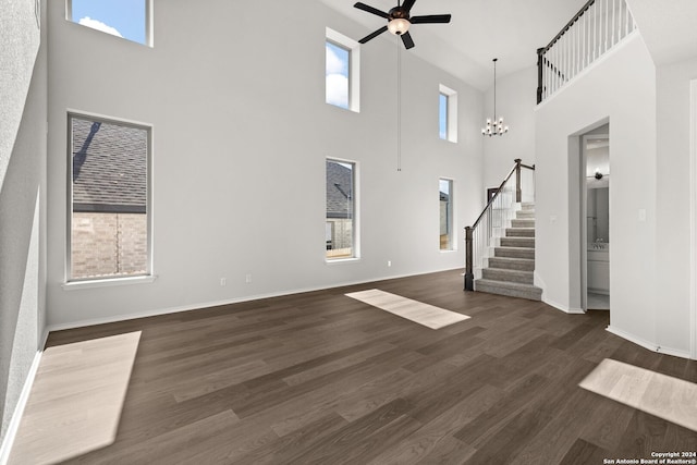 unfurnished living room with a towering ceiling, dark wood-type flooring, and a healthy amount of sunlight