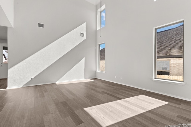 unfurnished living room with dark wood-type flooring and a high ceiling