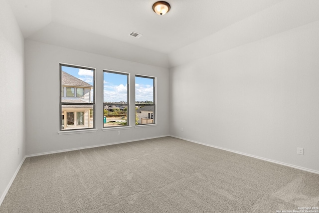 carpeted empty room featuring lofted ceiling